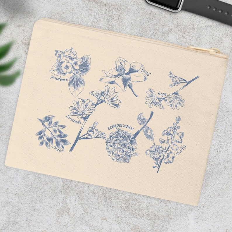 May include: A beige canvas zippered pouch with blue floral illustrations and the words "faith", "hope", "charity", "prudence", "fortitude", "justice", "temperance" printed on it.