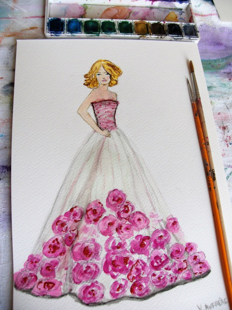 Pode incluir: Pintura em aquarela de uma ilustra&ccedil;&atilde;o de moda. A obra de arte retrata uma mulher em um vestido rosa e branco adornado com rosas rosas. A mulher tem cabelo loiro e est&aacute; em p&eacute; com uma m&atilde;o na cintura. Pinc&eacute;is e uma paleta de aquarela no fundo.