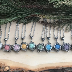 May include: Ten silver necklaces with lava stone pendants in various colors, including white, pink, light green, dark green, blue, and purple. The pendants are encased in a wire cage design.