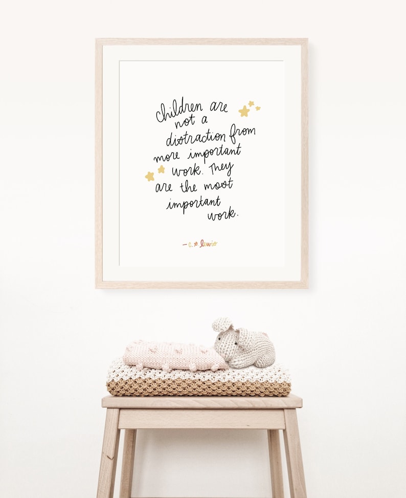 May include: A framed print with a white background and black text that reads "Children are not a distraction from more important work. They are the most important work. - C.S. Lewis". The text is surrounded by gold stars.