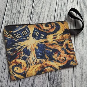 May include: A rectangular pouch with a black zipper and a black handle. The pouch features a colorful, swirling design in shades of blue, yellow, and orange, with two blue police boxes.