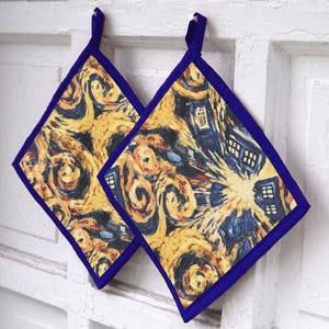 May include: Two diamond-shaped pot holders featuring a print of swirling yellow and dark blue patterns with blue police box icons. Each pot holder has a solid dark blue fabric border and a matching dark blue fabric loop for hanging purposes.