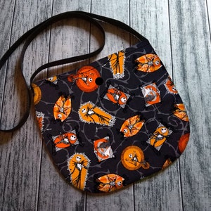 K&ouml;nnte beinhalten: Schwarze Umh&auml;ngetasche mit einem Halloween-Motiv mit Jack Skellington aus Nightmare Before Christmas. Der Druck zeigt orange und wei&szlig;e Jack Skellington-Figuren auf schwarzem Hintergrund.