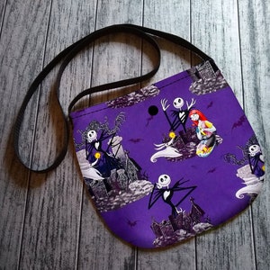 Puede incluir: Un bolso bandolera morado con un estampado repetido de personajes de Pesadilla antes de Navidad, incluyendo a Jack Skellington y Sally. El bolso tiene una correa negra y est&aacute; hecho de tela. El fondo incluye im&aacute;genes de una casa encantada y murci&eacute;lagos.