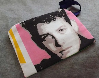 Könnte beinhalten: Eine weiße Reißverschlusstasche mit einem Schwarzweißbild eines Männergesichts. Der Hintergrund ist rosa mit einem gelben Streifen.