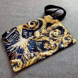 Peut inclure: Une pochette en tissu bleu et jaune avec un imprimé de ciel étoilé et un TARDIS bleu. La pochette a une anse en tissu noir.