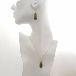 May include: A green stone pendant necklace and matching earrings. The pendant and earrings are teardrop shaped.