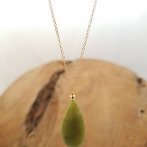 May include: A gold chain necklace with a teardrop-shaped green stone pendant.