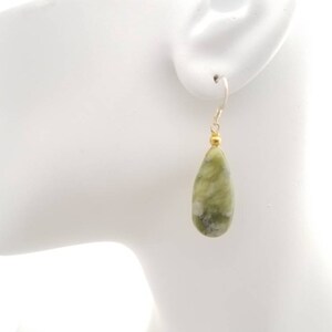 May include: Green and white teardrop-shaped earrings with gold beads and silver hooks.