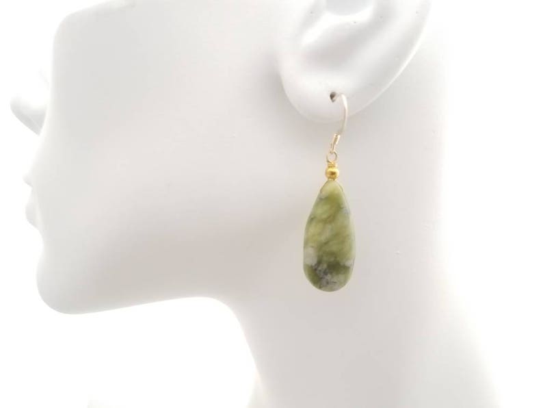 May include: Green and white teardrop-shaped earrings with gold beads and silver hooks.