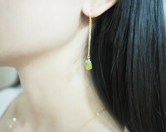 May include: Gold chain earrings with a green gemstone dangling from the end.