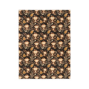 Könnte beinhalten: Ein schwarzer Stoff mit einem sich wiederholenden Muster aus braunen Affen, die auf Ästen mit gelben Blättern sitzen. Die Affen sind cartoonartig und haben braunes Fell, weiße Gesichter und schwarze Augen.