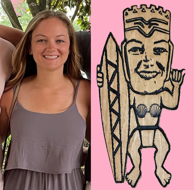 May include: A wooden cutout of a person holding a surfboard. The person is wearing a crown and a seashell bikini top. The cutout is painted in brown and black.