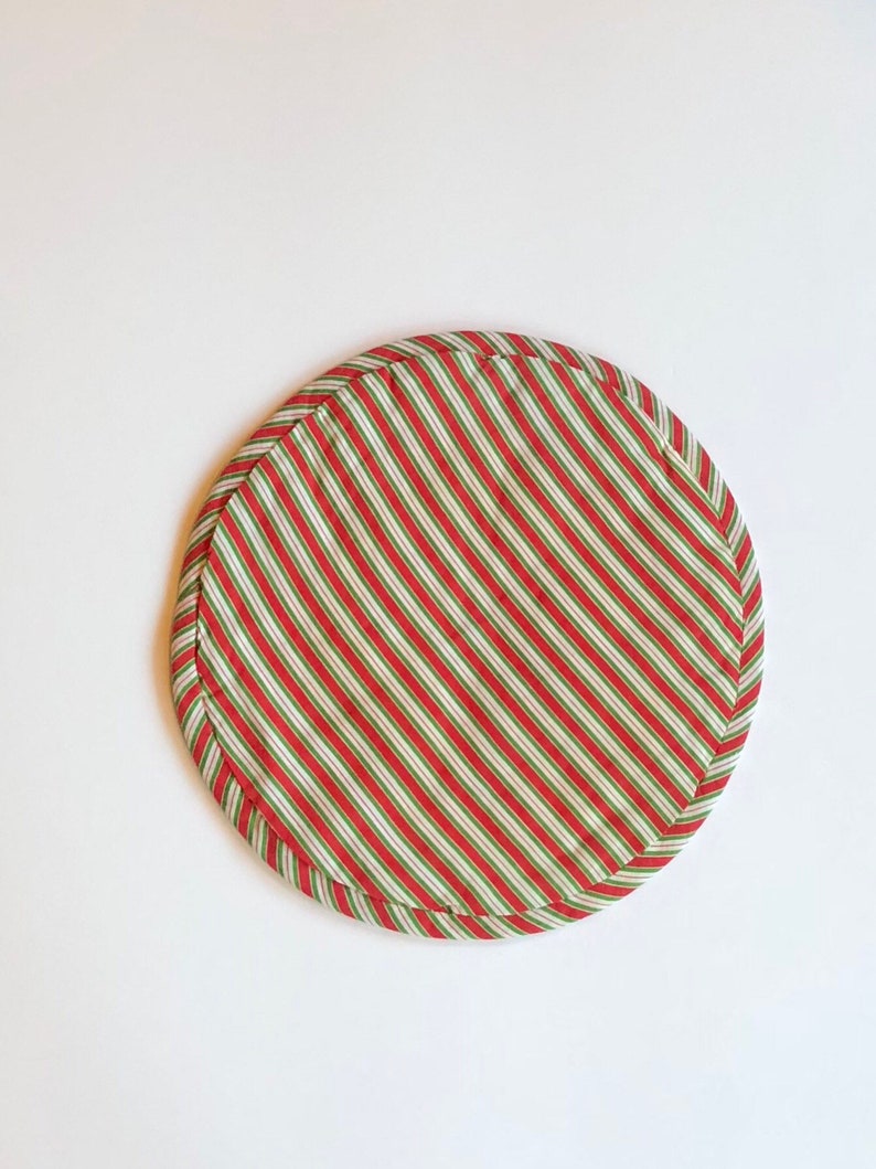 Op de afbeelding: Ronde placemat van stof met rode en groene strepen.