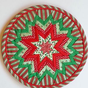 Op de afbeelding: Een ronde, rode, groene en witte gestikte kerstversiering met een stervorm.