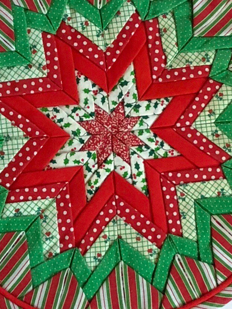 Op de afbeelding: Een stervormig quiltblok in rood en groen met een hulstpatroon. Het quiltblok is gemaakt van stofresten die in een geometrisch patroon aan elkaar zijn genaaid.