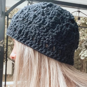 May include: A black crocheted beanie with a textured pattern. The beanie is worn on a person's head.