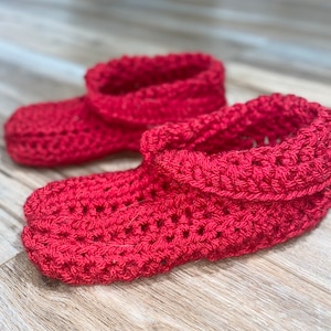 May include: A pair of red crocheted slippers. The slippers have a folded cuff and a textured stitch pattern.