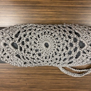 Puede incluir: Un porta-esterilla de yoga de crochet gris con cierre de cordón. El porta-esterilla está hecho de un patrón delicado y calado y tiene un diseño simple y elegante.