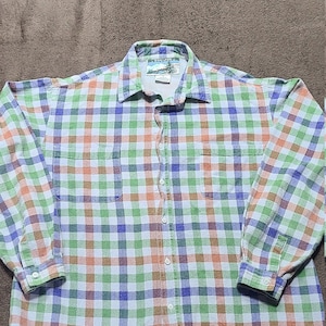 May include: A long-sleeved plaid shirt with a green, blue, orange, and white checkered pattern. The shirt has a button-up front and two chest pockets.
