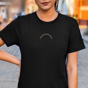 Może przedstawiać: Czarny T-shirt z małym haftowanym tęczą w kolorze fioletowym, żółtym i białym.