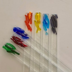 May include: Six clear glass rods with colourful glass accents. The accents are in shades of green, red, blue, yellow, orange, and purple.