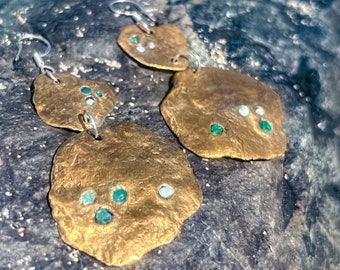Un hermoso juego de aretes de bronce con incrustaciones de pequeños pedazos de plástico marino reciclado en un collar de plata esterlina 100% reciclada con corte de diamante.