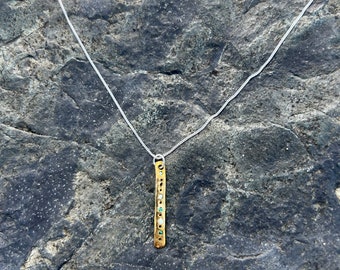 Un magnifique pendentif en bronze incrusté de minuscules morceaux de plastique marin recyclé sur un collier en argent sterling 100 % recyclé taillé en diamant.