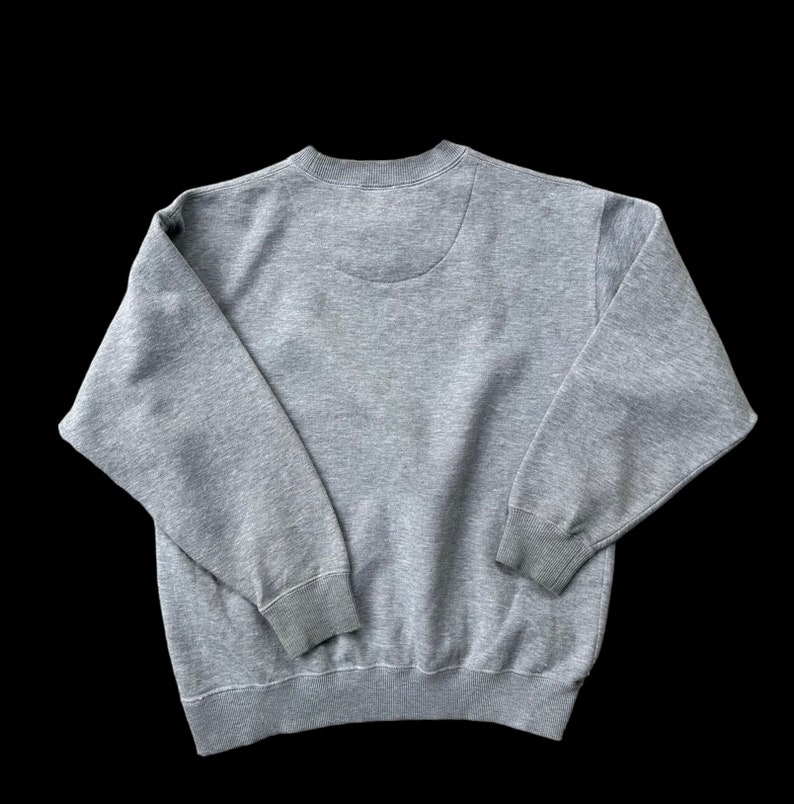 K&ouml;nnte beinhalten: Ein grauer Pullover mit langen &Auml;rmeln und einem Rundhalsausschnitt.