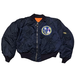 Könnte beinhalten: Eine dunkelblaue Bomberjacke mit Reißverschluss und einem Patch auf der linken Seite mit der Aufschrift "USS NIMITZ 1975".
