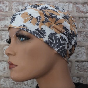 May include: A white, grey and brown patterned turban-style head covering. The fabric is soft and flowing.