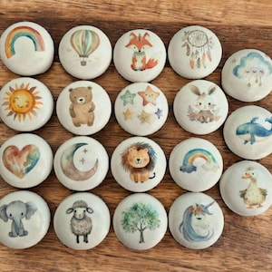 May include: Set of 18 painted round stones with various designs, including animals, rainbows, clouds, stars, a moon, a heart, a hot air balloon, a dreamcatcher, and a tree. The stones are white with colourful designs.