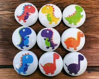 May include: Set of 9 white round ceramic knobs with colorful dinosaur designs. The dinosaurs are in various poses and colors, including green, blue, orange, purple, and red.