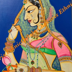May include: A vibrant painting of a woman in traditional Indian attire. She wears a pink blouse, green and gold sari, and ornate jewelry. The background is a solid blue. The woman holds a pink lotus flower. The text "Chris L Clinic Gifts Ethnic" is in the upper right corner.