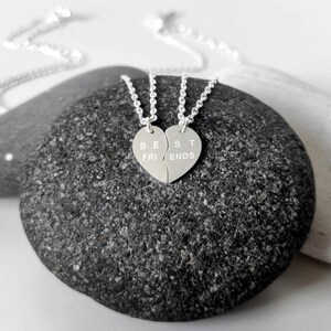 A close-up of the two necklaces with a dangling silver heart pendant. The necklace is perfect for best friends and symbolizes their unbreakable bond.