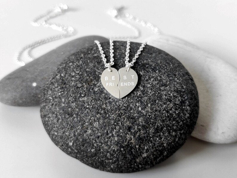 A close-up of the two necklaces with a dangling silver heart pendant. The necklace is perfect for best friends and symbolizes their unbreakable bond.
