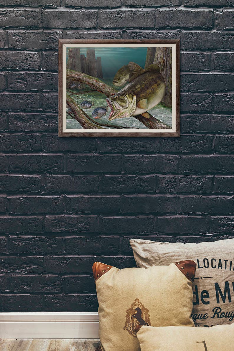 May include: A framed illustration of a largemouth bass with its mouth open, as if it is about to eat a smaller fish. The bass is swimming in a murky green water with a log in the foreground. There are several smaller fish swimming around the bass.