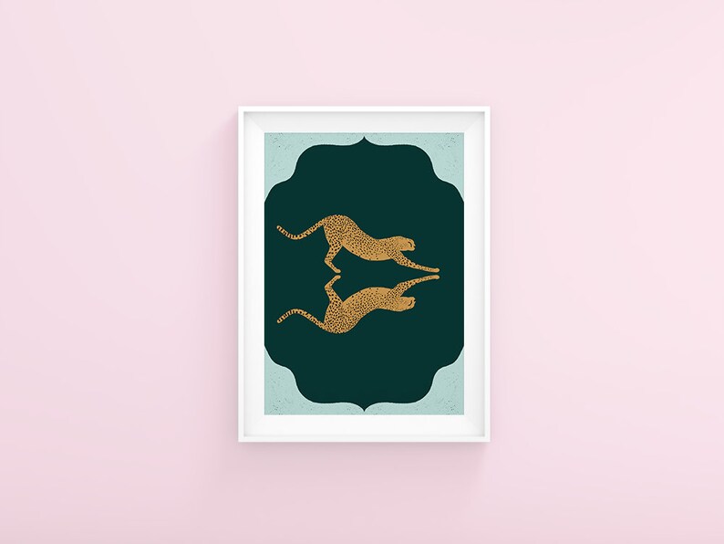 May include: A framed print with a dark green background and a light blue border. Two gold cheetah silhouettes are facing each other in a mirrored pose.