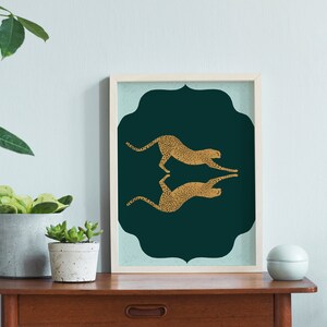 May include: A framed print with a teal green background and two gold cheetah silhouettes facing each other. The cheetah silhouettes are mirrored images of each other.