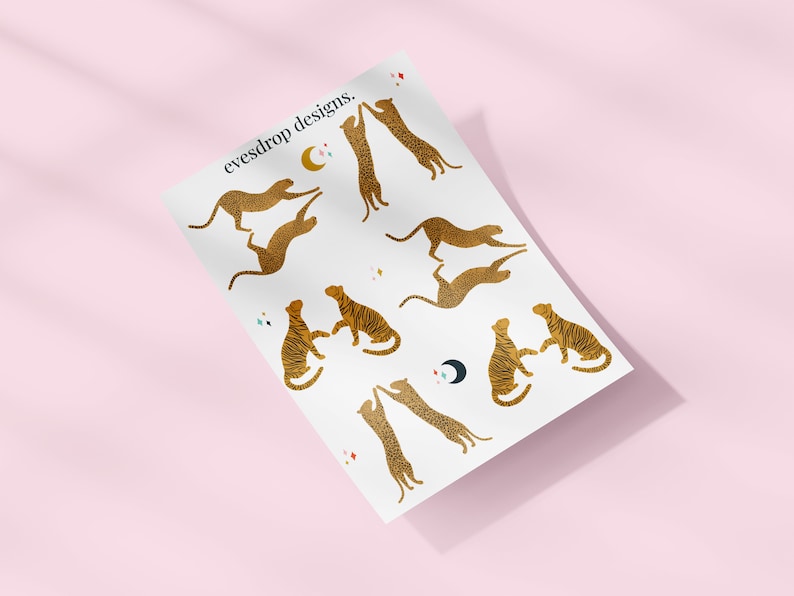 Puede incluir: Una hoja de papel blanco con ilustraciones de leopardos en silueta dorada en varias poses. El papel tiene el texto "eyesdrop designs." impreso en negro en la parte superior.