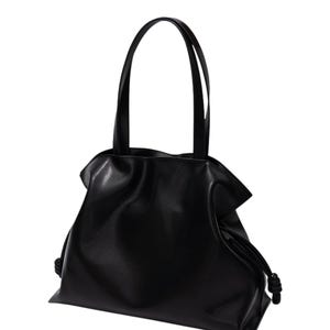 May include: A black tote bag with two long handles and a drawstring closure. The bag is made of a smooth, matte material and has a gathered design at the top. The handles are attached to the bag with a simple stitch.