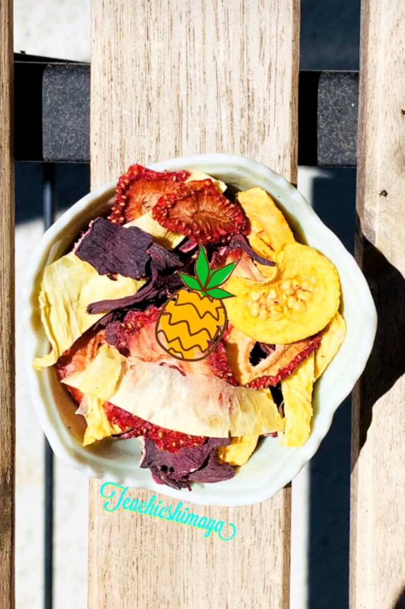 May include: A white bowl filled with a variety of dried fruits, including pineapple, strawberries, and mango. The fruits are a mix of red, yellow, and purple.