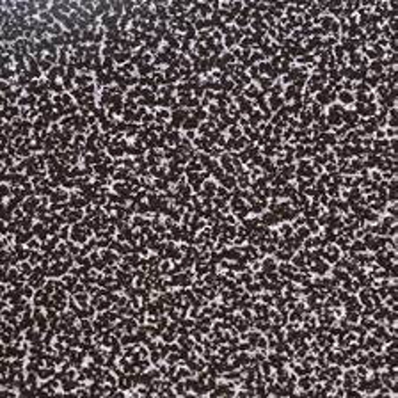 May include: Close-up of a dark brown textured surface with a speckled white pattern. The surface has a rough, uneven texture.