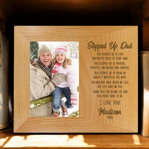 May include: A wooden picture frame with a photo of a man and a girl. The frame has an engraved message that reads "Stepped Up Dad" and includes a poem about the love and support of a stepdad. The poem ends with "I love you!" and is signed "Madison 2024".
