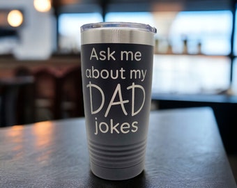 May include: A gray stainless steel tumbler with a white inscription that reads "Ask me about my DAD jokes".