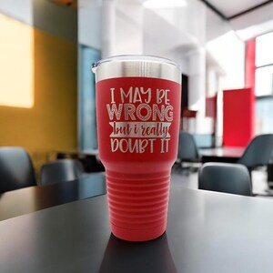May include: Red stainless steel tumbler with a white inscription that reads "I may be wrong but I really doubt it".