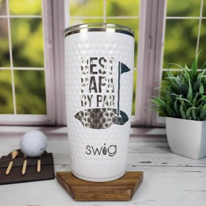 May include: White insulated tumbler with a textured surface and the text "BEST PAPA BY PAR" in a golf-themed design. Includes a golf ball and tee holder. The tumbler is approximately 25 cm tall.
