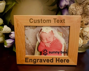 May include: A wooden picture frame with a photo of a baby girl sleeping. The frame has the text "Custom Text" and "Engraved Here" on it. The text "sunny box" is also visible in the photo.