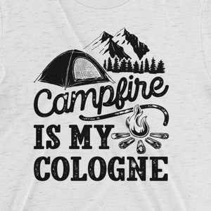 May include: A white t-shirt with a black graphic design of a tent, campfire, and trees. The text "Campfire is my Cologne" is printed on the shirt.