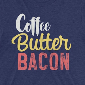 May include: A navy blue t-shirt with the text "Coffee Butter Bacon" in white, yellow, and pink lettering.